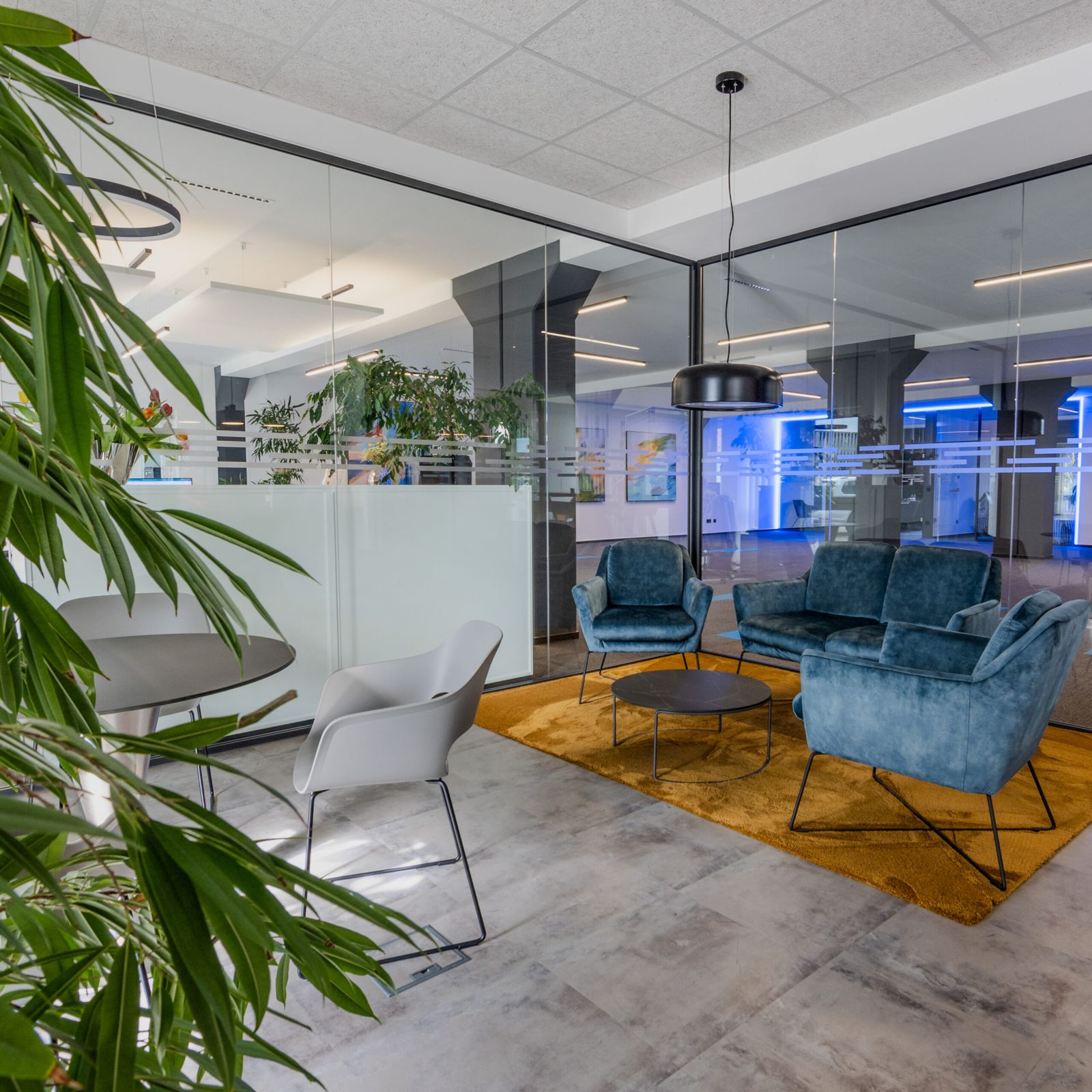 Lounge mit blauen Sesseln vor verglasten Büros